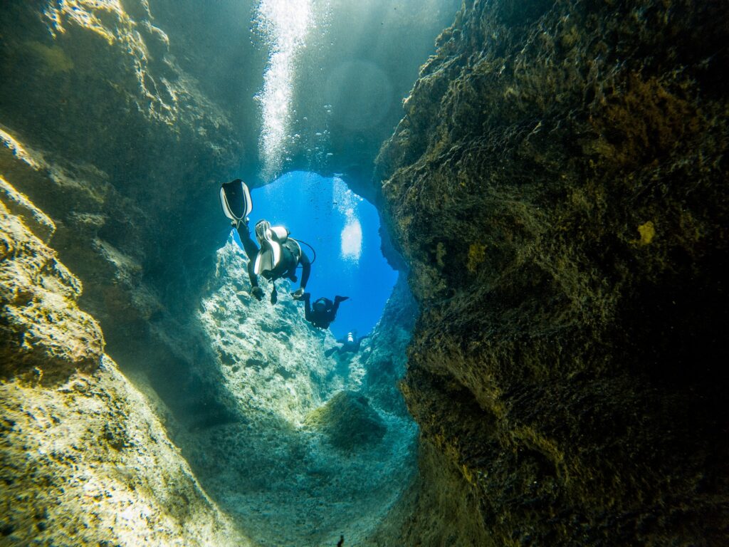 Scuba divers swimming through a canyon